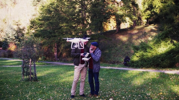 Senior father and his young son with drone in nature, talking. Slow motion.