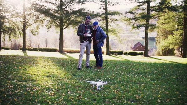 Senior father and his young son with drone in nature, talking. Slow motion.