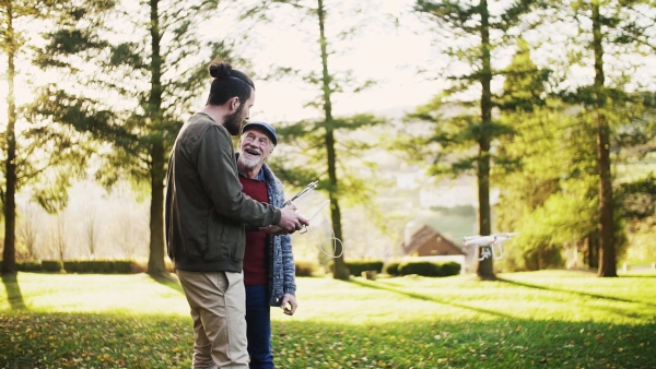 Senior father and his young son with drone in nature, talking. Slow motion.