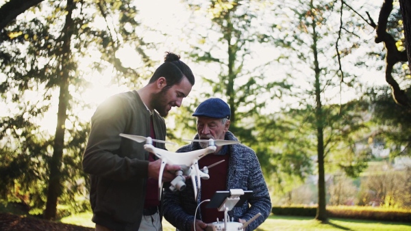 Senior father and his young son with drone in nature, talking. Slow motion.