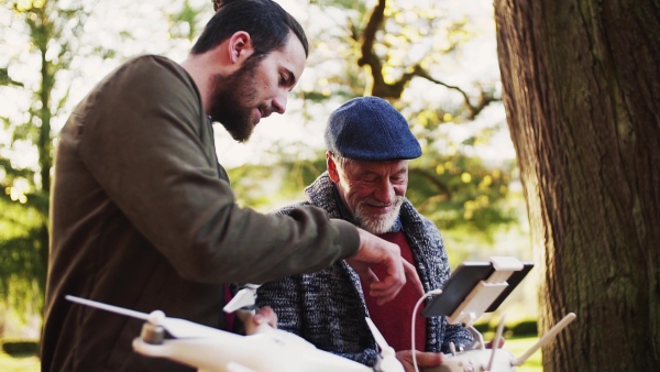 Senior father and his young son with drone in nature, talking. Slow motion.