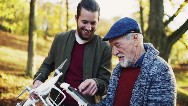 Senior father and his young son with drone in nature, talking. Slow motion.