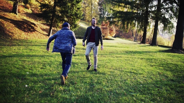 Senior father and his young son walking in nature, having fun. Slow motion.