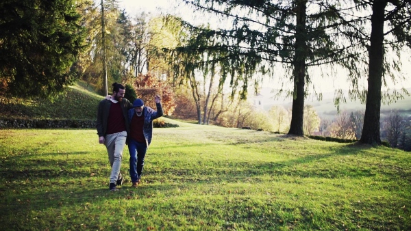 Senior father and his young son walking in nature, having fun. Slow motion.