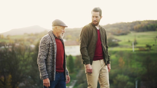 Senior father and his young son walking in nature, having fun. Slow motion.