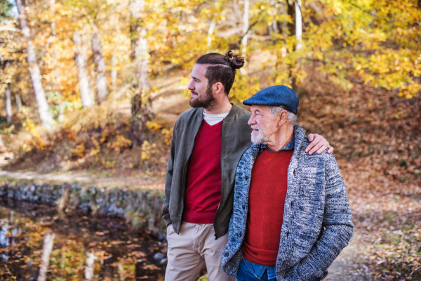 Senior father and his young son walking in nature, talking.