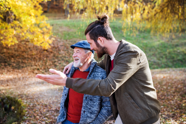 As senior father and his son standing in nature, talking.