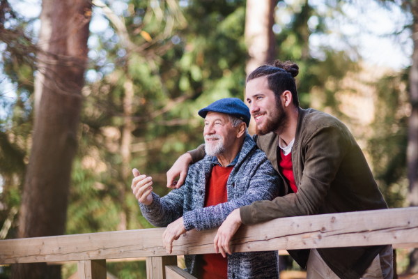 A senior father and his son on walk in nature, standing and talking.