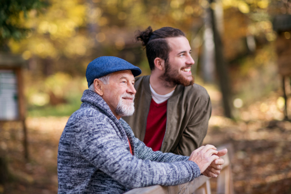 A senior father and his son on walk in nature, standing and talking.