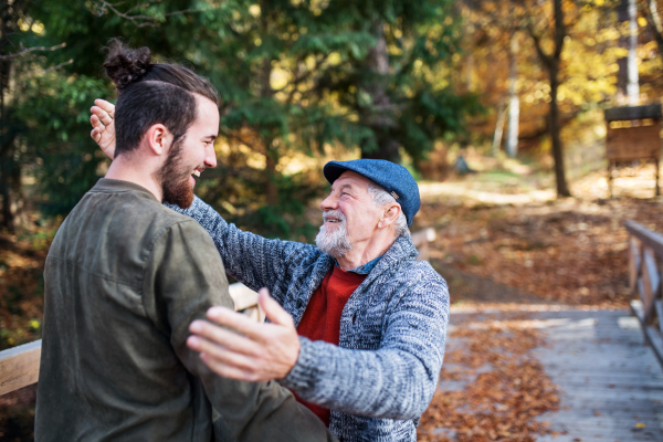 A senior father and his son on walk in nature, hugging and talking.