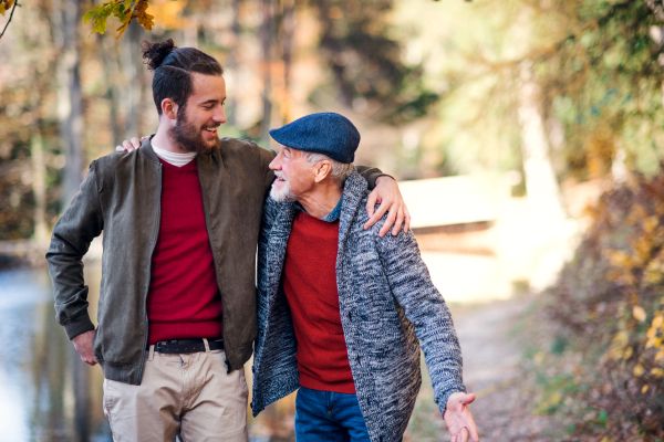 Senior father and his young son walking in nature, talking.