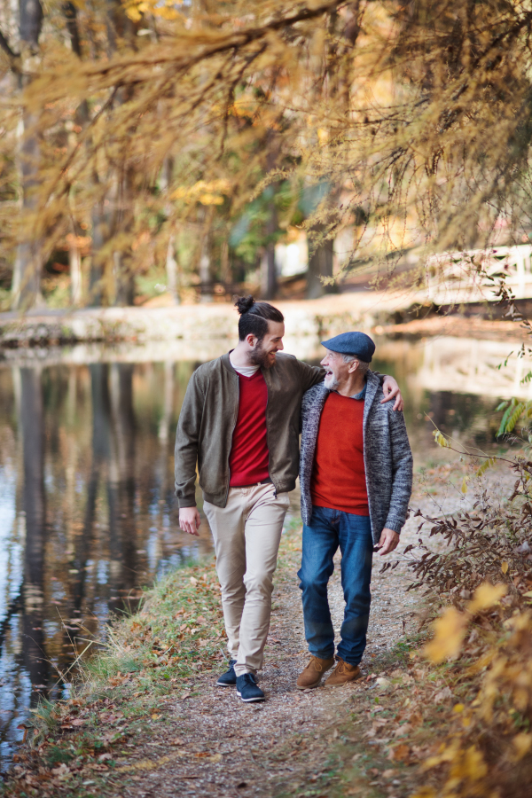 Senior father and his young son walking in nature, talking.