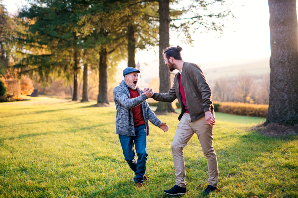 Laughing senior father and his young son on a walk in nature, shaking hands.