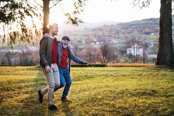 A senior father and his son on walk in nature, talking.