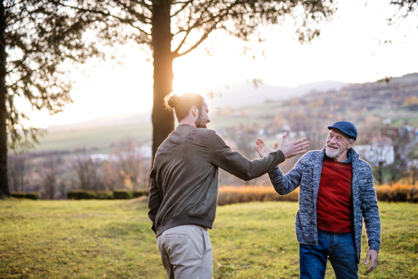 Senior father and his young son on a walk in nature, giving high five.