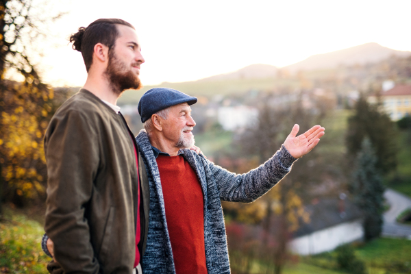 A senior father and his son on walk in nature, talking.