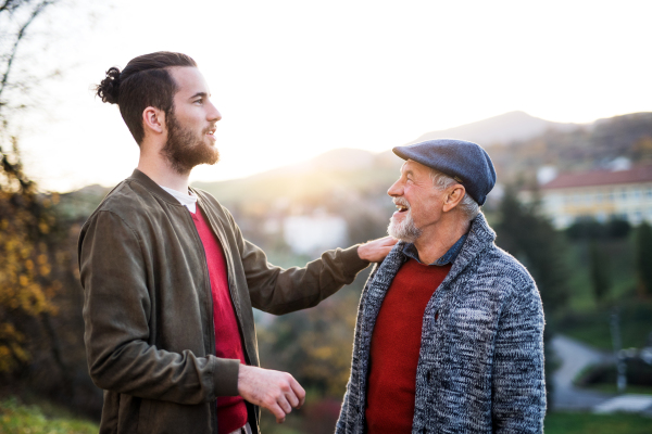 Senior father and his young son on a walk in nature, talking.