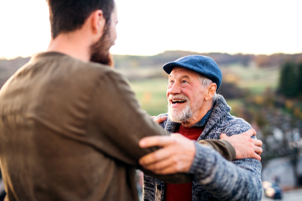 Senior father and his young son on a walk in nature, talking.