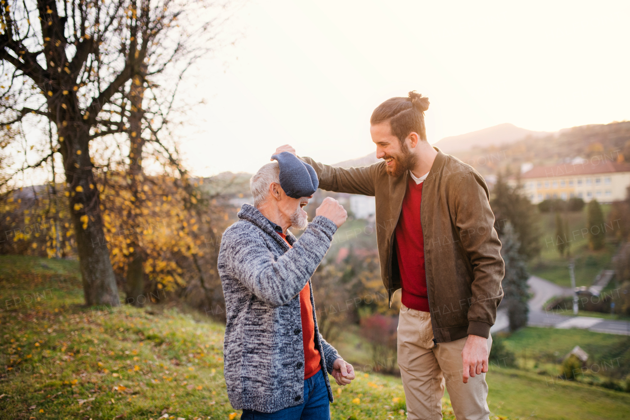 A young man and his senior father in nature, having fun.