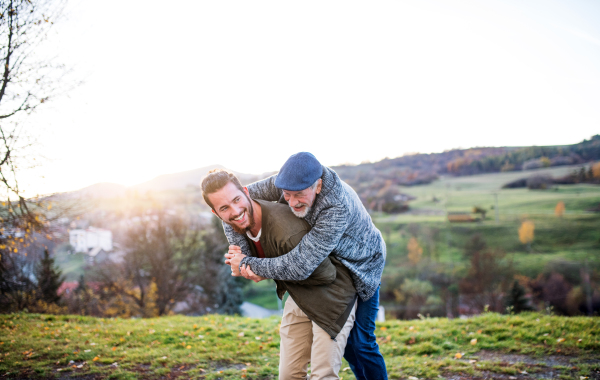 Senior father and his young son walking in nature, having fun.