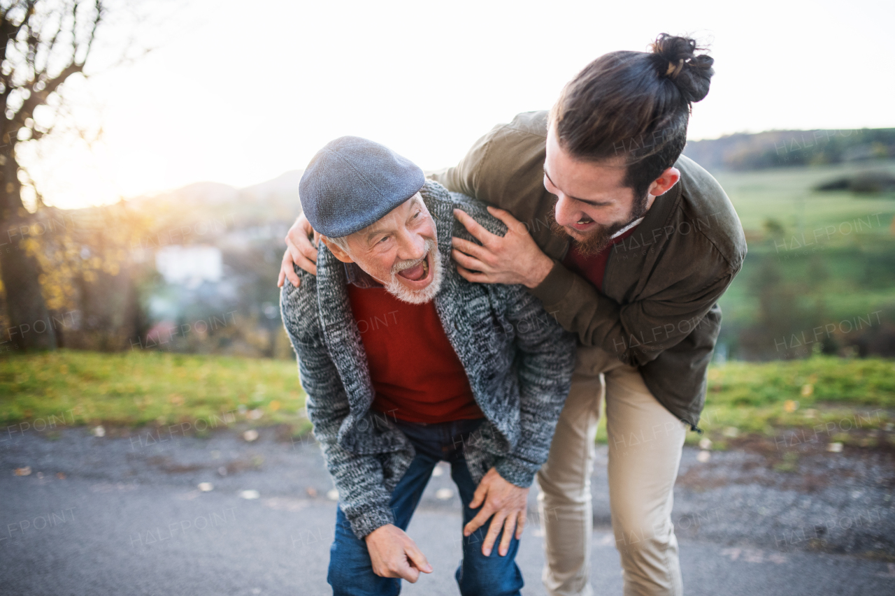 A young man and his senior father on a walk in nature, laughing.