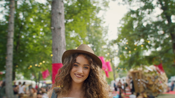 A young woman with hat at summer festival, looking at camera.