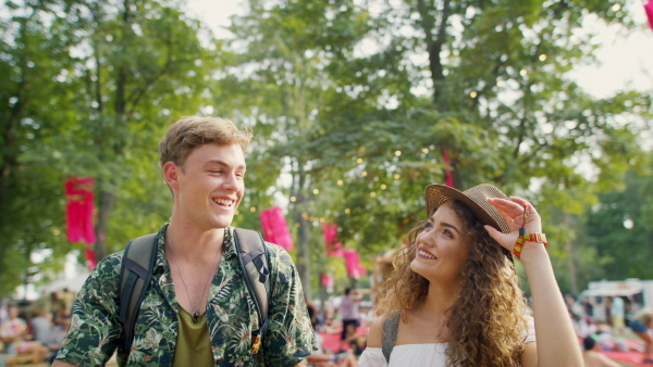 Young couple at summer festival or camping holiday, walking and talking.