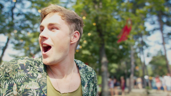 A young man at summer festival, having fun, dancing and singing.