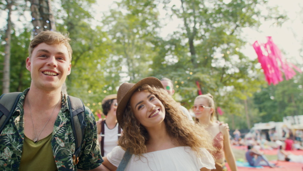 Young couple at summer festival or camping holiday, walking and talking.