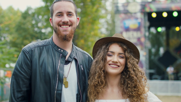 Front view portrait of young couple at summer festival, dancing arm in arm.