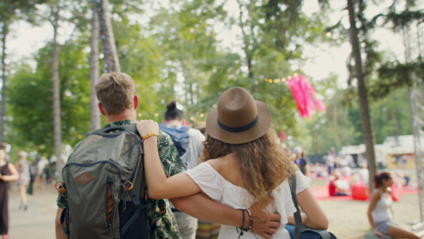 Rear view of group of young friends at summer festival or camping holiday, walking.