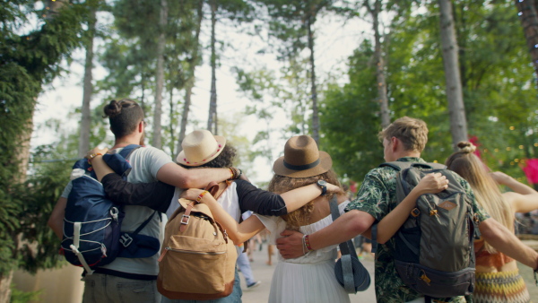 Rear view of group of young friends at summer festival or camping holiday, walking.