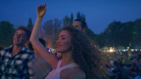 A group of cheerful young friends dancing at summer festival.