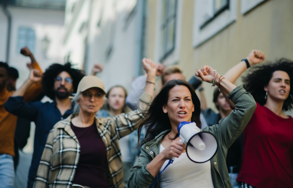 Group of people activists with megaphone protesting on streets, strike and demonstration concept.