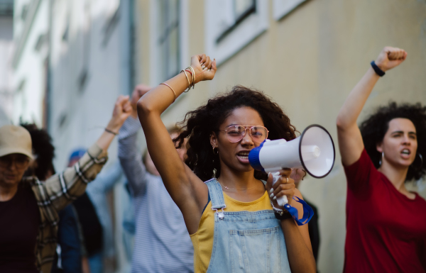 Group of people activists with megaphone protesting on streets, strike and demonstration concept.