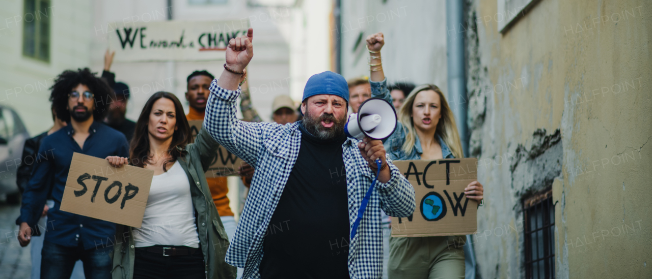 Group of people activists with megaphone protesting on streets, strike and demonstration concept.