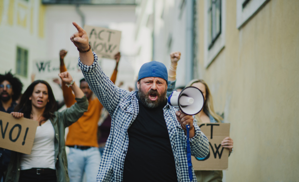 Group of people activists with megaphone protesting on streets, strike and demonstration concept.