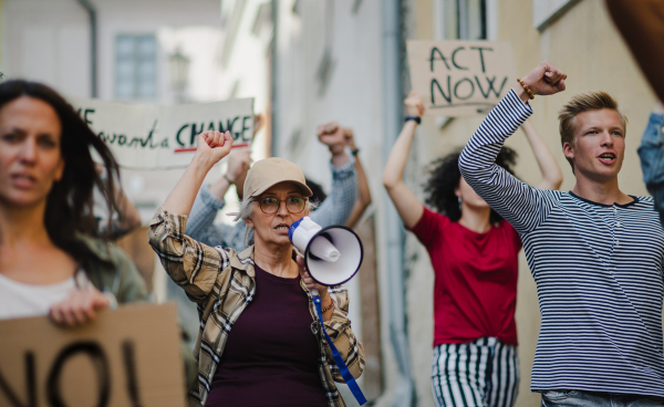 Group of people activists with megaphone protesting on streets, strike and demonstration concept.