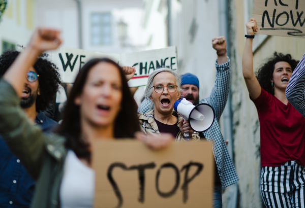 Group of people activists with megaphone protesting on streets, strike and demonstration concept.