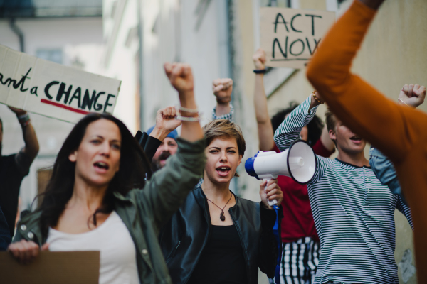 Group of people activists with megaphone protesting on streets, strike and demonstration concept.