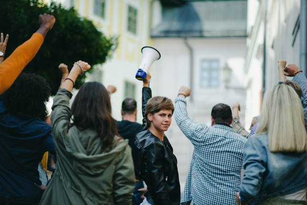 Portrait of young woman with megaphone protesting on streets, strike and demonstration concept.