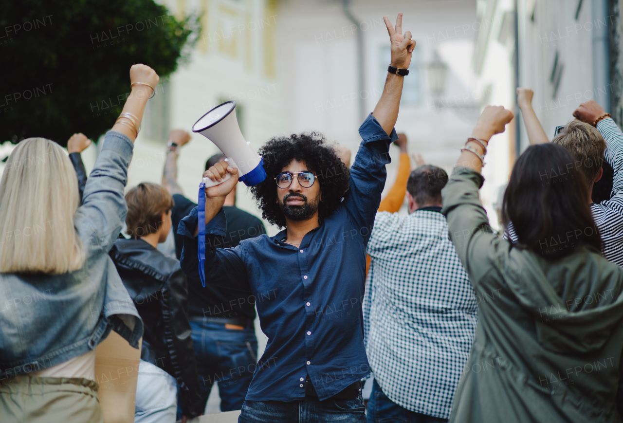 Group of people activists with megaphone protesting on streets, strike and demonstration concept.