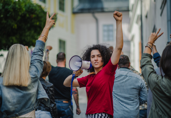 Group of people activists with megaphone protesting on streets, strike, demonstration and coronavirus concept.