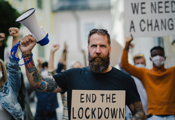 Front view of people with placards and posters on public demonstration, end of lockdown and coronavirus concept.