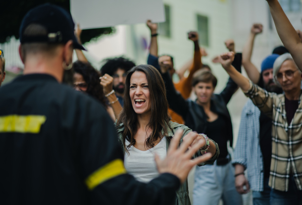 Police stopping group of shouting people activists with raised fists protesting on streets, BLM demonstration concept.