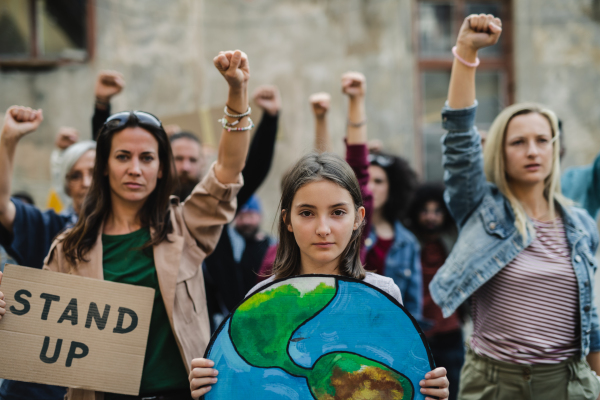 Group of people activists with raised fists protesting on streets, strike and demonstration concept.