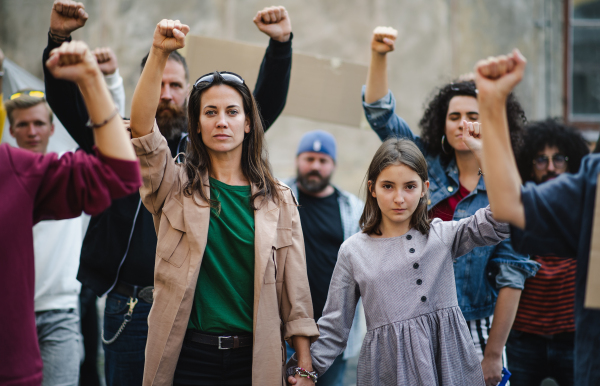 Group of people activists with raised fists protesting on streets, strike and demonstration concept.