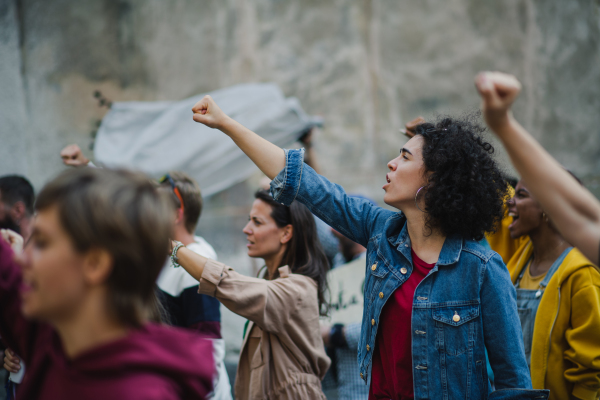 Group of people activists with megaphone protesting on streets, strike and demonstration concept.