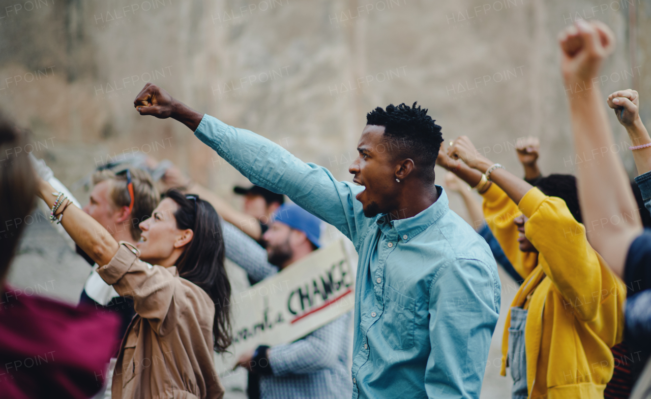 Side view of group of people activists with raised fists protesting on streets, BLM demonstration concept.