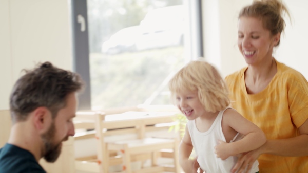 A young family with small boy indoors in bedroom getting dressed.